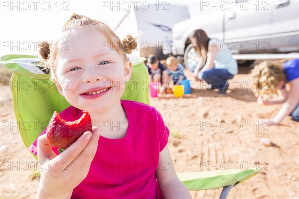 Caucasian girl eating strawberry while camping