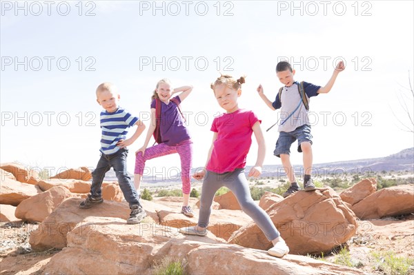 Caucasian boys and girls dancing on rocks