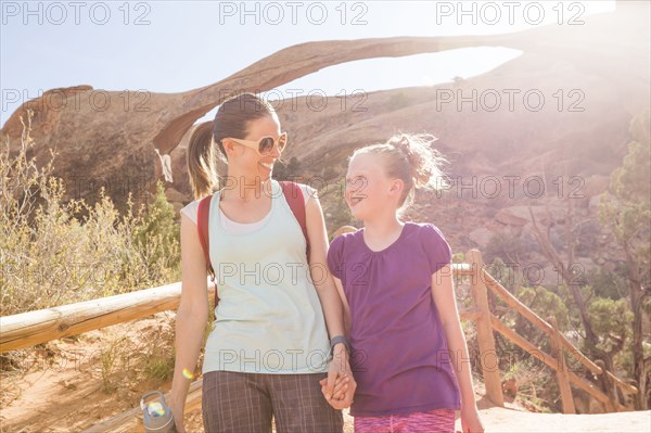 Caucasian mother and daughter holding hands and walking