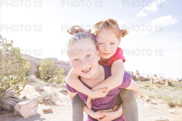 Caucasian girl carrying sister piggyback