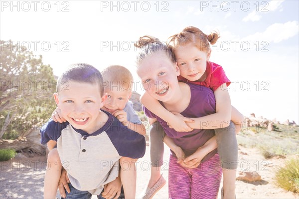 Caucasian children carrying boy and girl piggyback