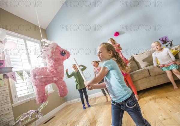 Caucasian girl hitting pinata at party