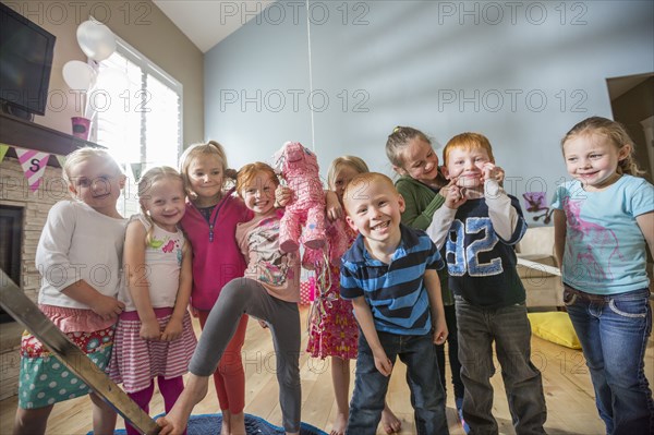 Caucasian children posing with pinata at party