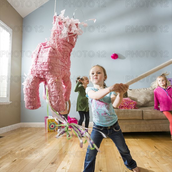 Caucasian girl hitting pinata at party