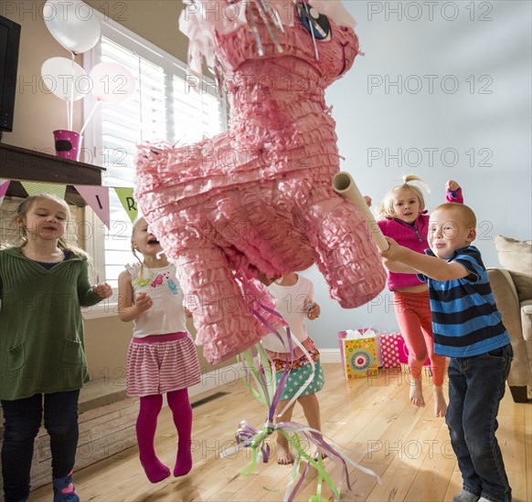 Caucasian boy hitting pinata at party