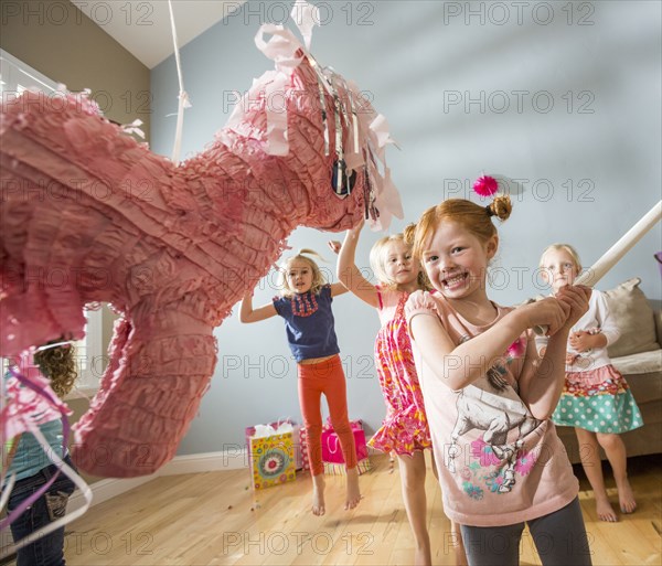 Caucasian girl hitting pinata at party