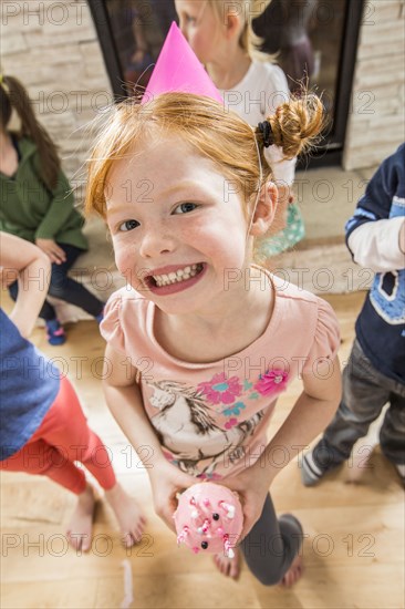 Caucasian girl wearing party hat holding cupcake