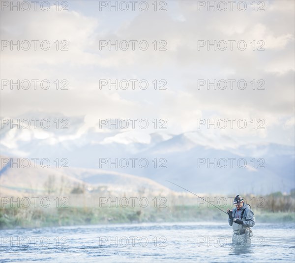 Caucasian man fly fishing in river