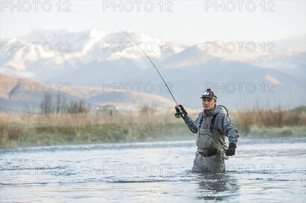 Caucasian man fly fishing in river