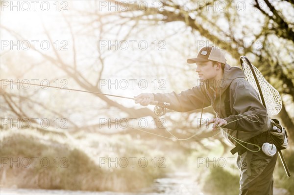 Caucasian man fly fishing in river