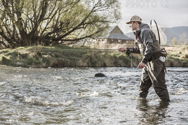 Caucasian man fly fishing in river