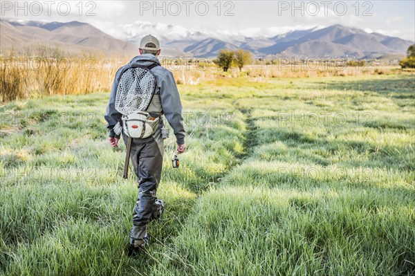 Caucasian man carrying fishing rod in field