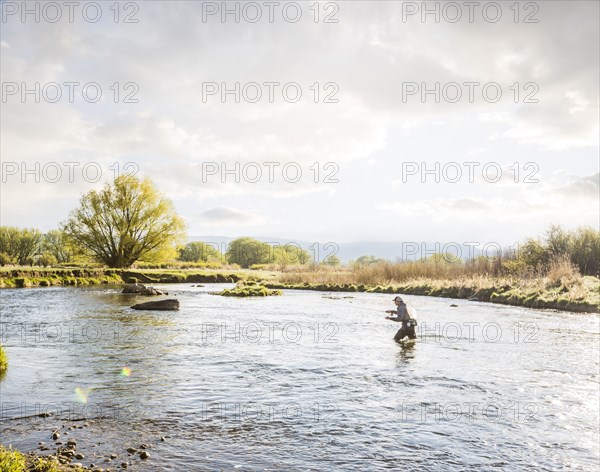 Caucasian man fly fishing in river