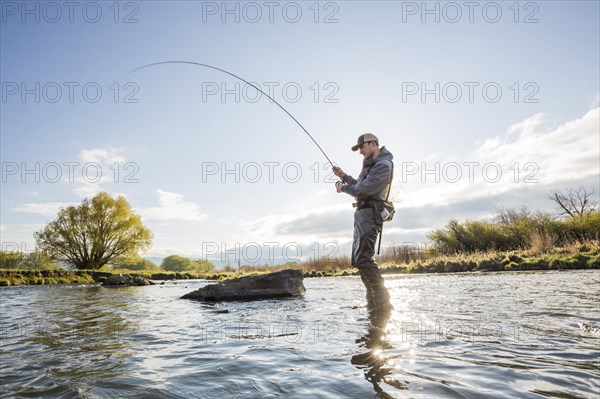 Caucasian man fly fishing in river