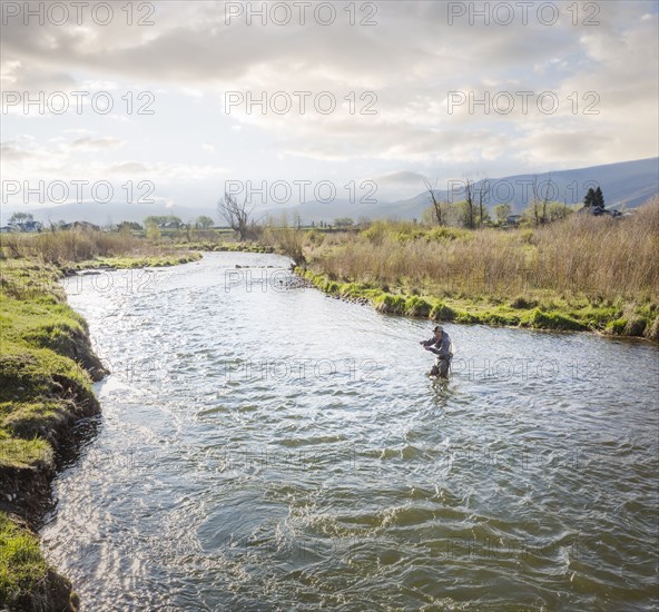 Caucasian man fly fishing in river
