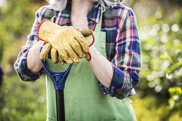 Caucasian woman wearing gloves holding shovel