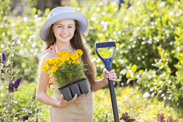 Caucasian girl holding tray of flowers in garden