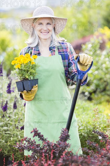 Caucasian woman holding tray of flowers in garden