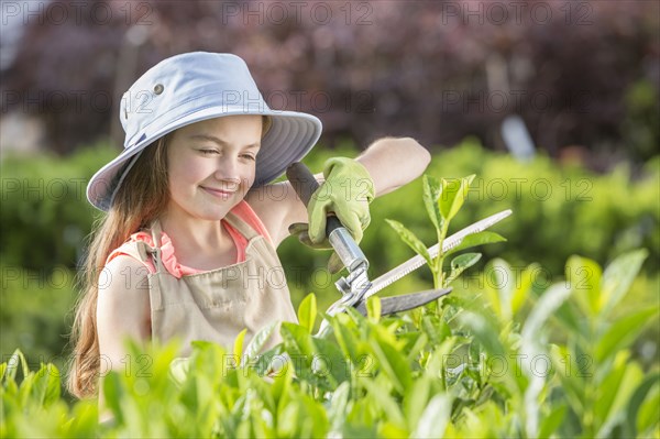 Caucasian girl pruning plants in greenhouse