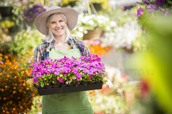 Caucasian woman holding potted plants in greenhouse