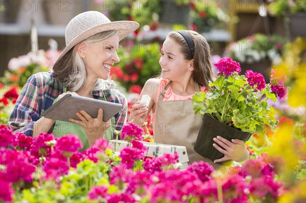 Caucasian grandmother and granddaughter using digital tablet in greenhouse