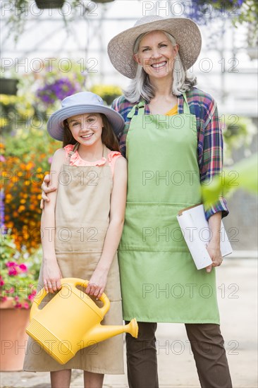 Caucasian grandmother and granddaughter posing in greenhouse