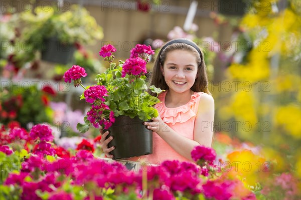 Caucasian girl holding potted plant in greenhouse