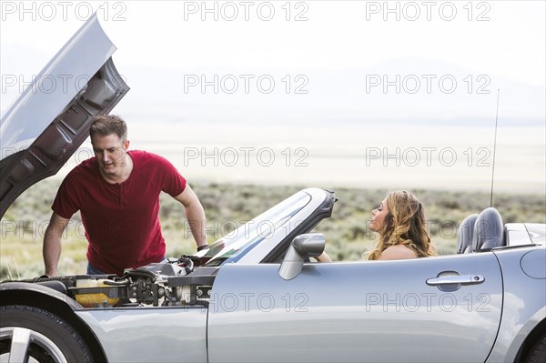 Caucasian man examining car engine at vehicle breakdown