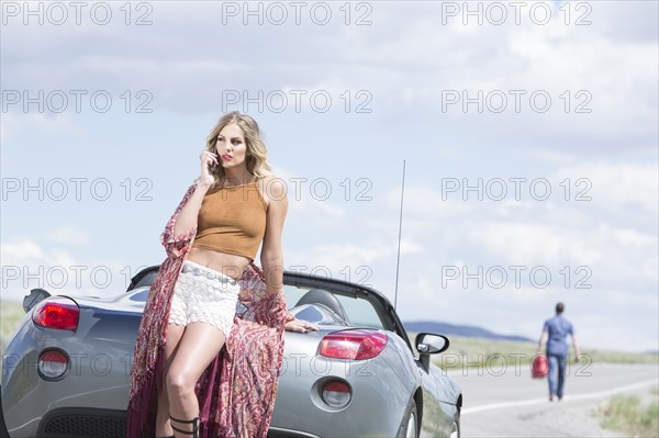 Caucasian woman talking on cell phone at vehicle breakdown