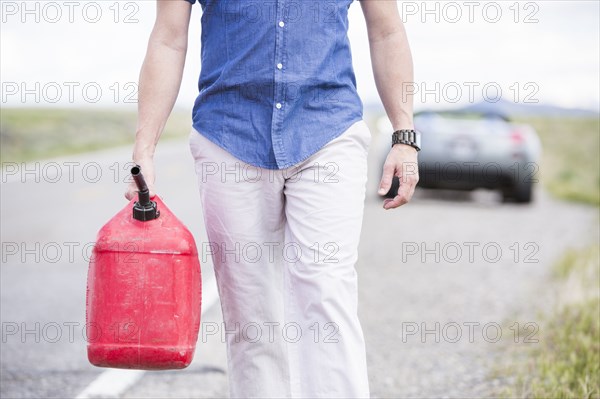 Caucasian man carrying gas on street