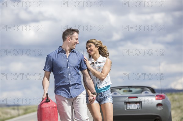 Caucasian couple carrying gas can on street