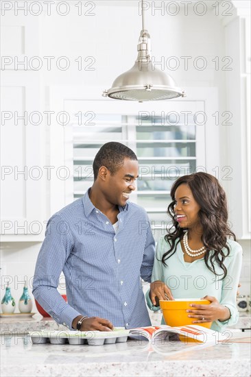 Black couple baking cupcakes in kitchen