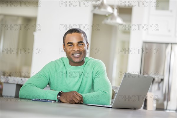 Black man sitting at table with laptop