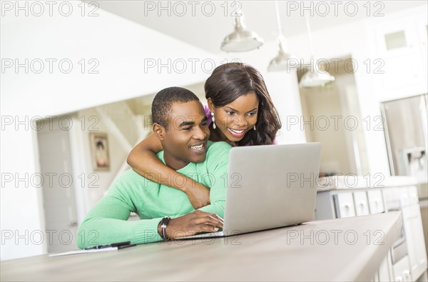 Black couple at table using laptop