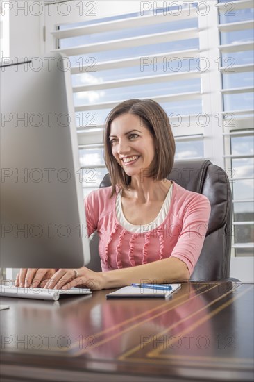 Caucasian businesswoman using computer at desk