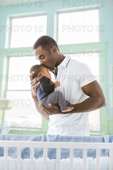 Black father kissing baby son on forehead