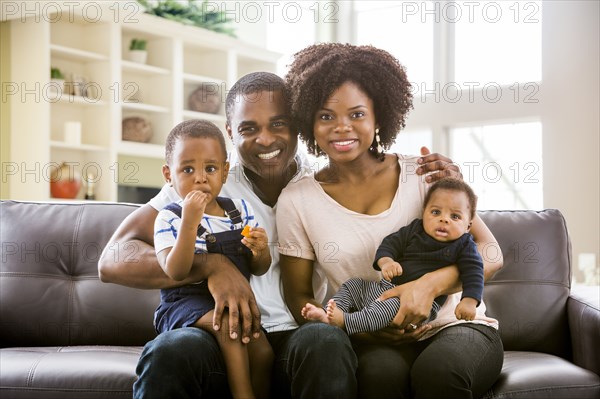 Smiling Black family posing on sofa
