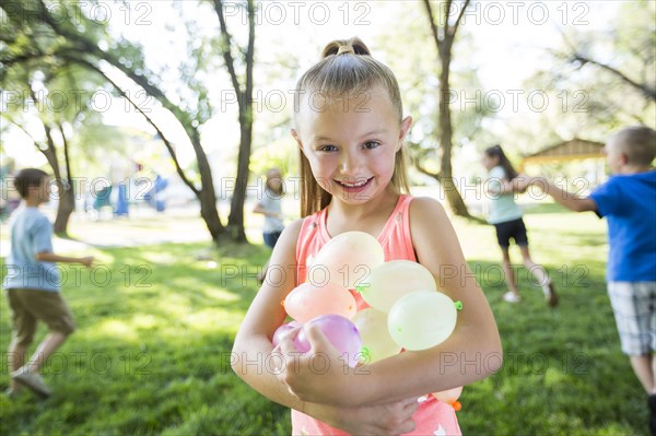 Caucasian girl holding water balloons