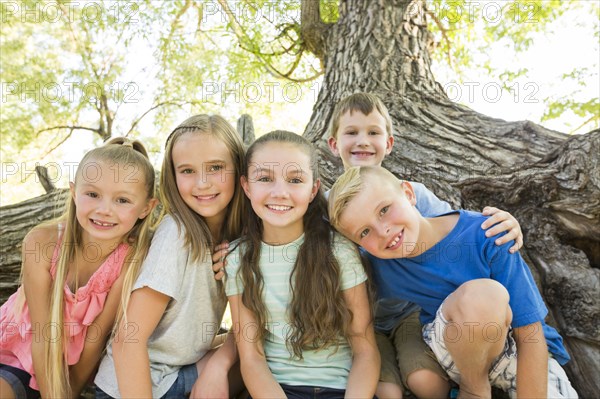 Caucasian boys and girls posing near tree