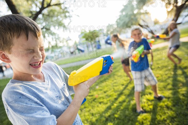 Caucasian boys and girls playing with squirt guns