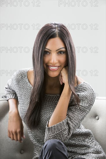 Portrait of smiling Indian woman sitting on sofa