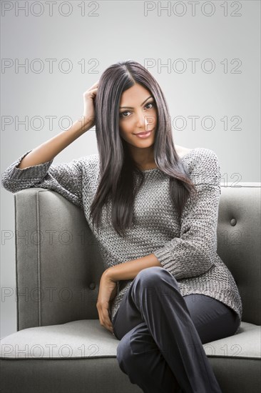 Portrait of smiling Indian woman sitting on sofa