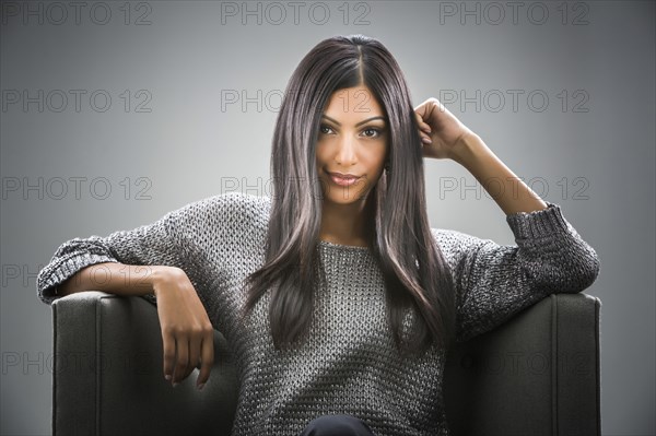 Portrait of smiling Indian woman sitting in armchair