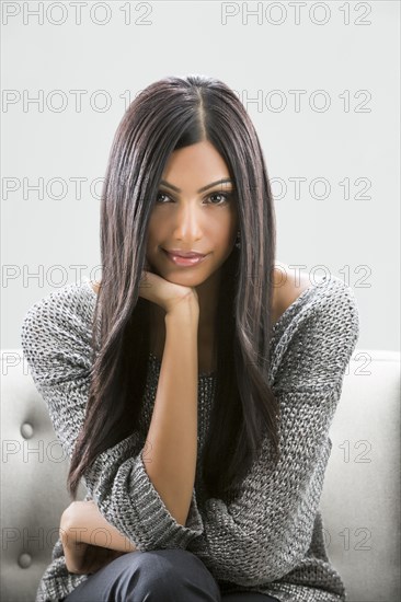 Portrait of serious Indian woman sitting on sofa