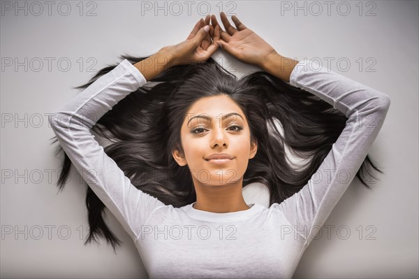 Portrait of smiling Indian woman laying on floor