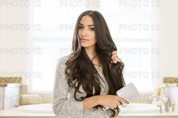 Mixed Race woman brushing hair in bathroom