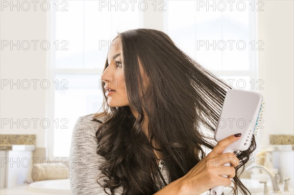 Mixed Race woman brushing hair in bathroom