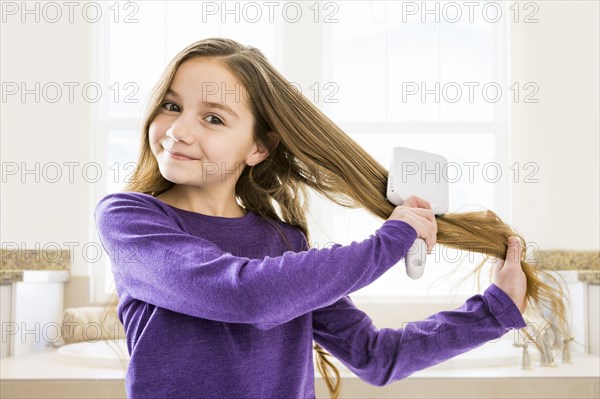 Caucasian girl brushing hair in bathroom