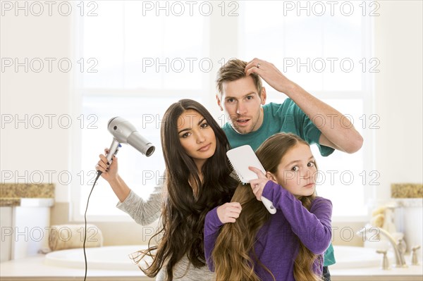 Family grooming hair in bathroom