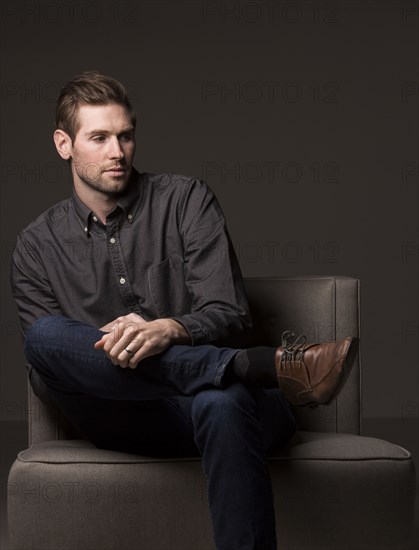 Serious Caucasian man sitting in armchair